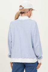 woman wearing a light blue striped long sleeve sweatshirt with a white trim and a white cap, viewed from the back