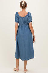 woman wearing a blue denim maternity dress with a ruffled neckline and short puff sleeves, seen from the back