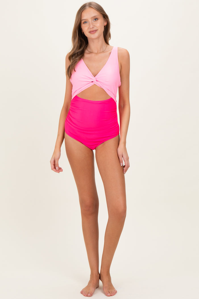 woman wearing a pink and light pink maternity swimsuit with a twist front and high-waisted bottom.