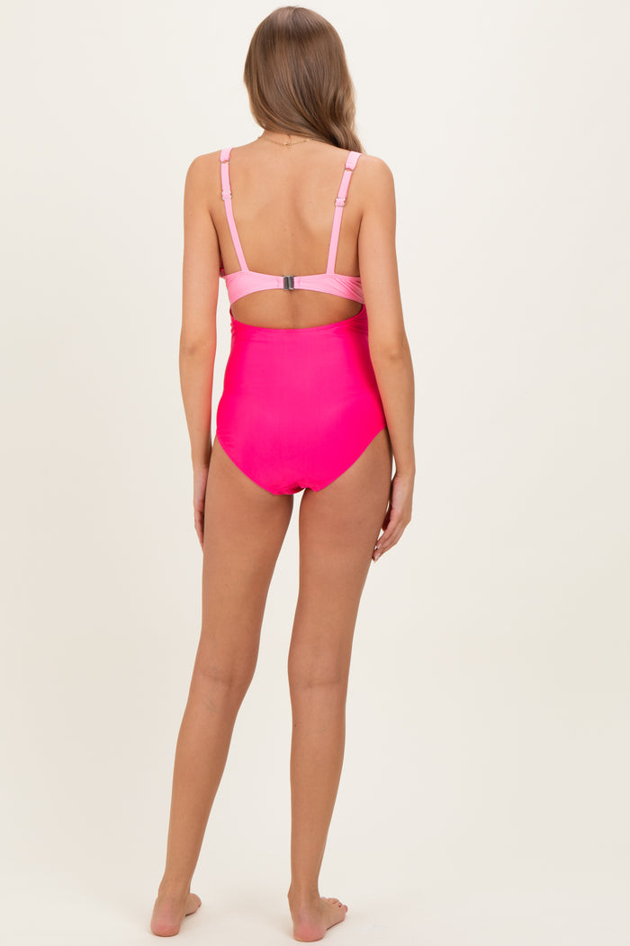 woman wearing a hot pink maternity swimsuit with adjustable straps and a back cutout detail