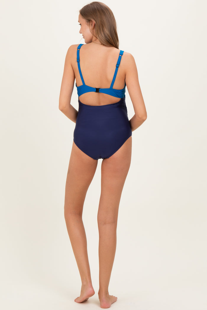 woman wearing a navy blue maternity swimsuit with adjustable blue straps and a back cutout design