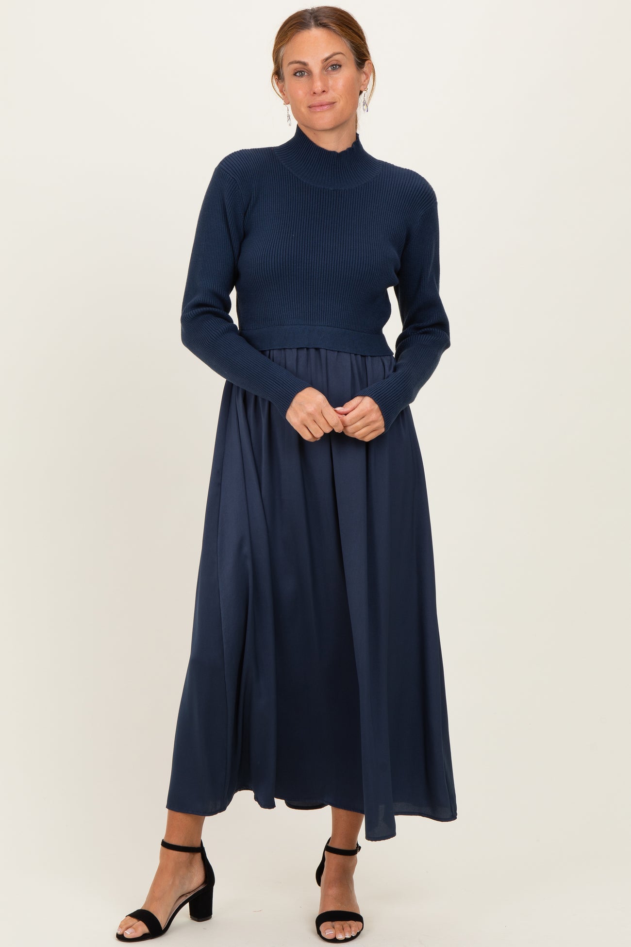 woman wearing a navy blue ribbed turtleneck sweater with a matching long skirt and black heeled sandals