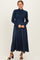 woman wearing a navy blue ribbed turtleneck sweater with a matching long skirt and black heeled sandals