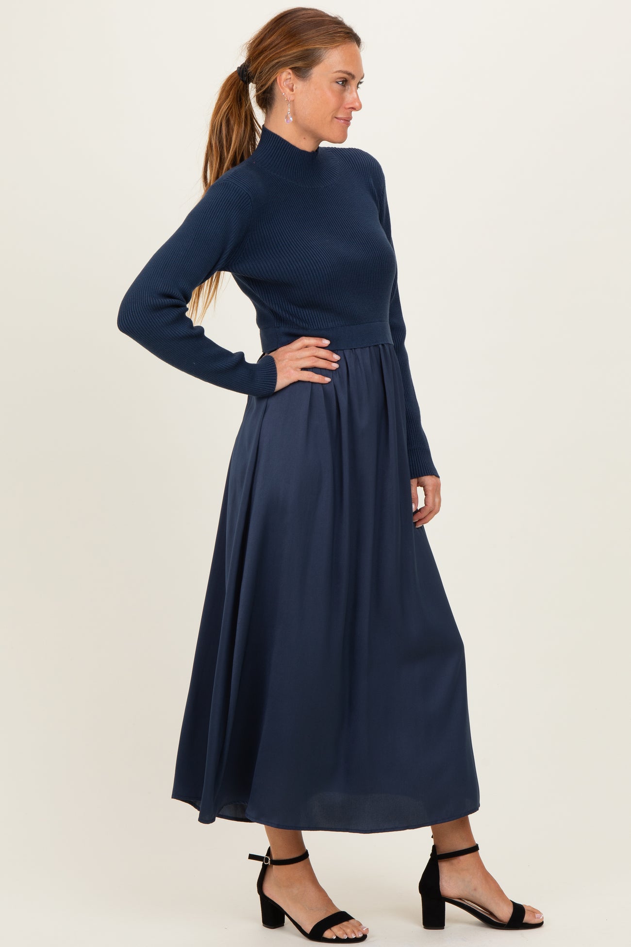 woman wearing a navy blue long sleeve ribbed top with a flowing maxi skirt and black heeled sandals