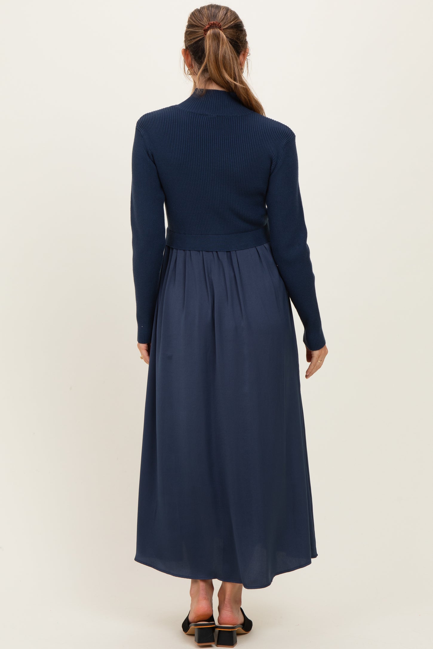woman wearing a navy blue maternity dress with a ribbed top and flowy skirt, showing her back