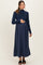 woman wearing a navy blue long sleeve maternity dress with a fitted top and flowing skirt, holding her baby bump