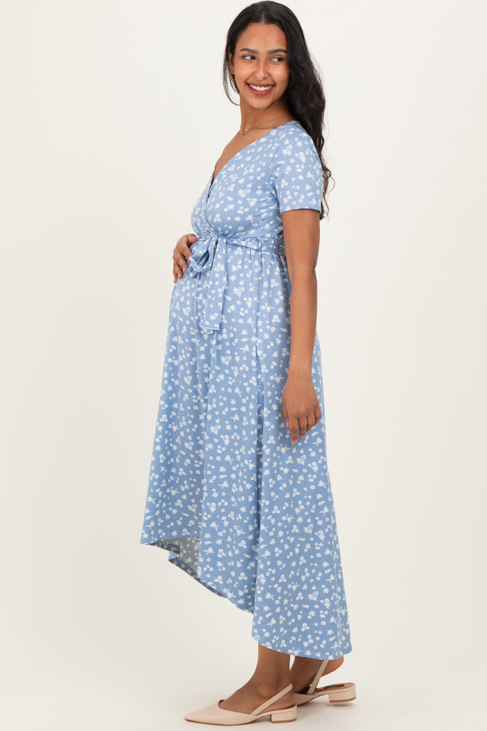 woman wearing a light blue floral maternity dress with a tie waist and an asymmetrical hem, showcasing her baby bump