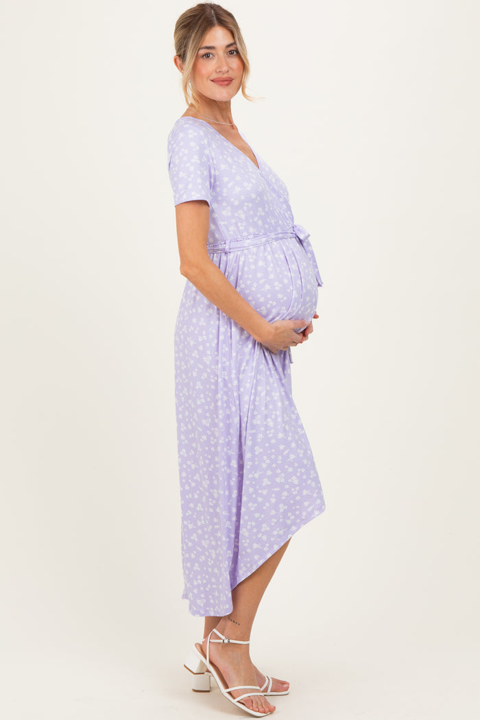 woman wearing a lilac floral wrap maternity dress and holding her baby bump