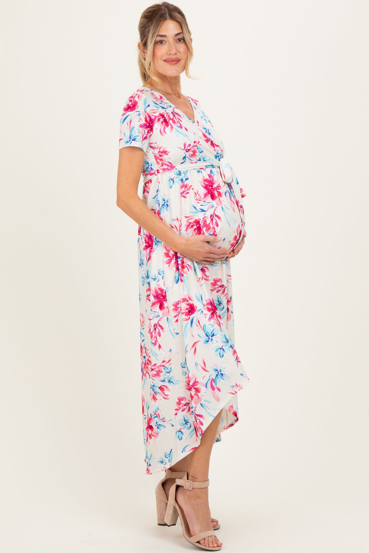 woman wearing a floral maternity maxi dress with a tied waist and holding her baby bump