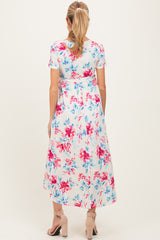 woman wearing a floral print maternity maxi dress with short sleeves and a cinched waist, showing a baby bump