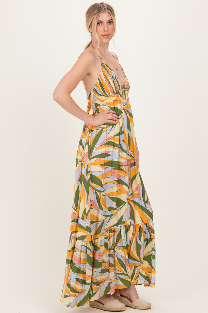 woman wearing a colorful maxi dress with a v-neck, spaghetti straps, and a tiered ruffle hem