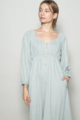 woman wearing a light blue long sleeve button-down dress with a square neckline and gathered details