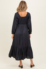 woman wearing a dark navy long sleeve maternity dress with a ruffled hem and open back detail