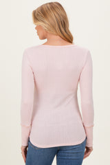 woman wearing a light pink long sleeve maternity top with a ribbed texture, seen from the back