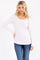 woman wearing a light beige long sleeve henley top with button details and paired with blue jeans