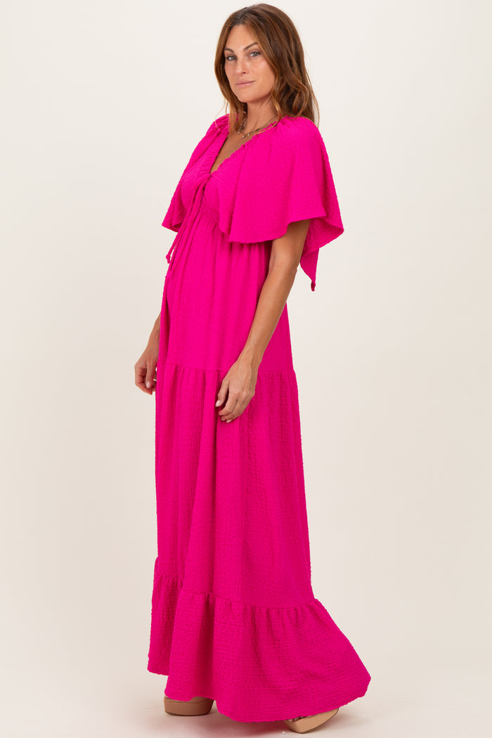 woman wearing a bright pink maxi dress with flutter sleeves and a tiered bottom