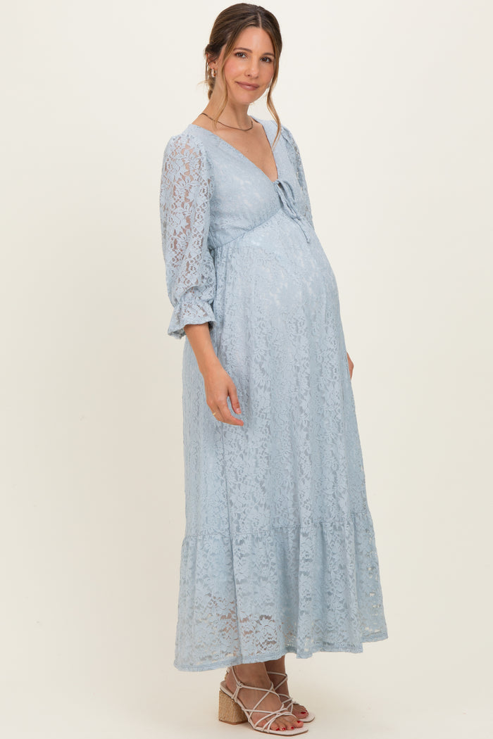 woman wearing a light blue lace maternity dress with a bow detail and a flowing silhouette, showing her baby bump