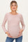 woman wearing a light pink ribbed maternity top and holding her baby bump