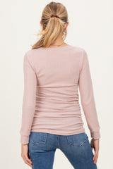 woman wearing a light pink long sleeve maternity top with a ribbed texture and gathered sides, showing her back