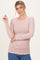 woman wearing a light pink ribbed long sleeve top with gathered side detail and a relaxed fit