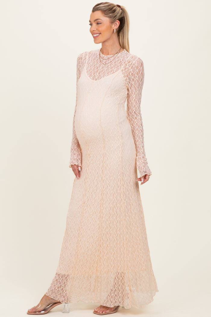woman wearing a light peach long sleeve maternity dress with a lace design and a visible baby bump
