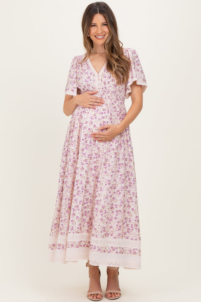 woman wearing a floral print maternity maxi dress with short sleeves and a v-neck, holding her baby bump
