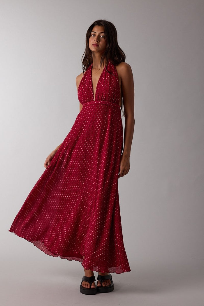 woman wearing a red halter neck maxi dress with white polka dots and a flowing skirt