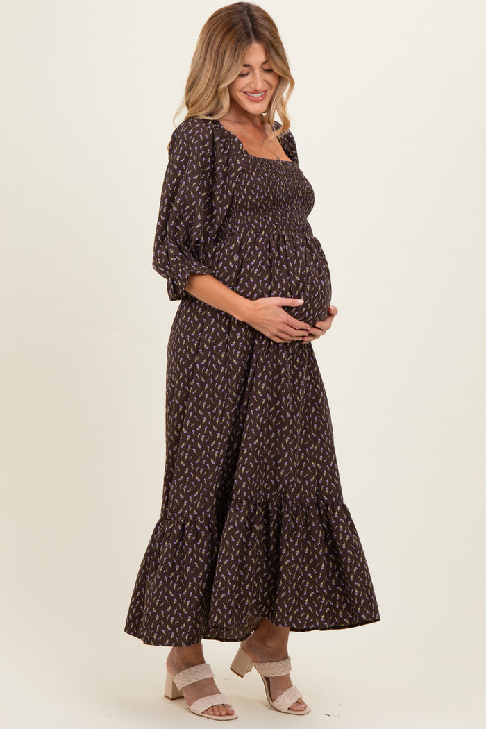woman wearing a dark brown floral maternity maxi dress with puff sleeves and a baby bump