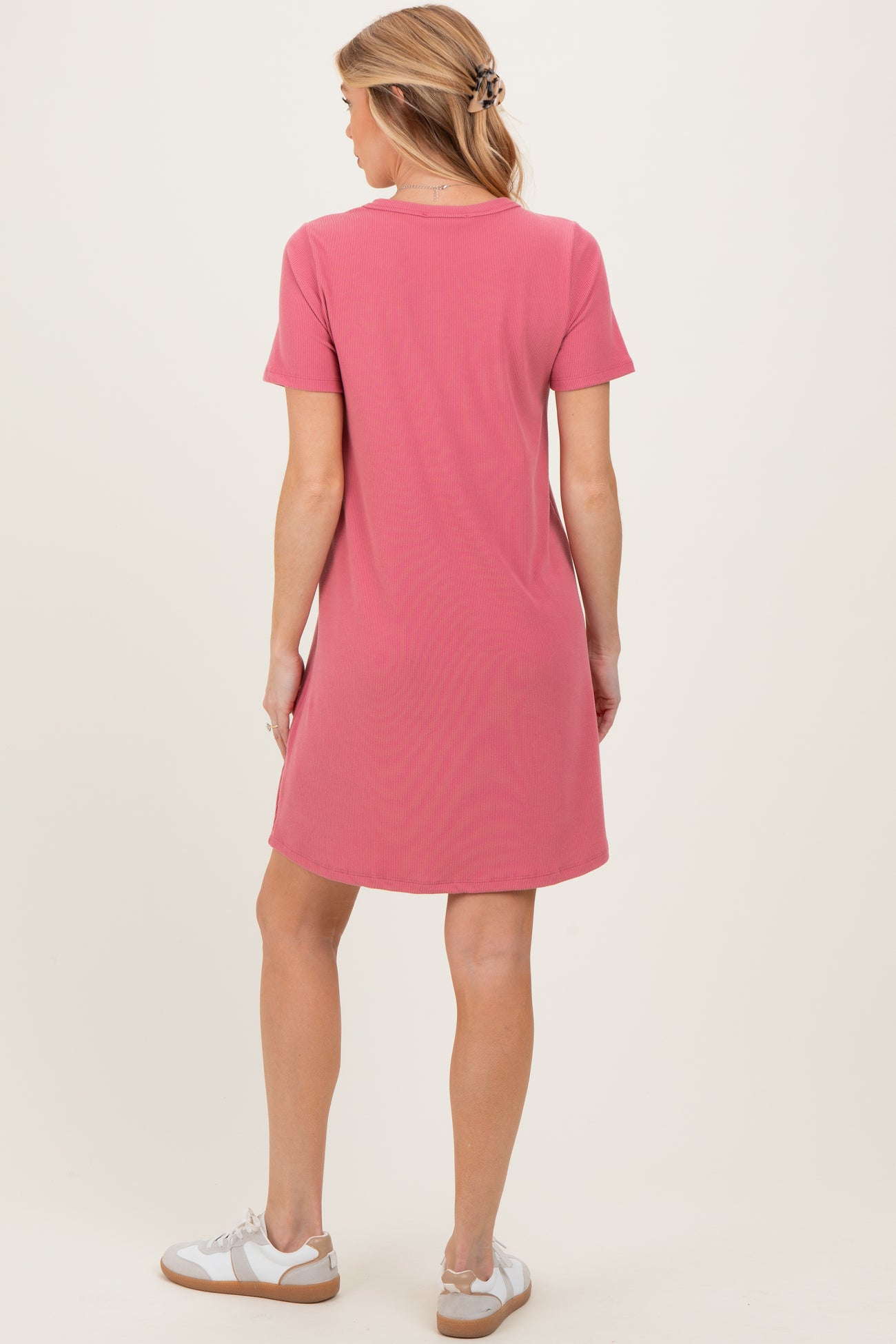 woman wearing a pink short sleeve maternity dress, standing with her back to the camera