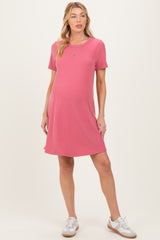 woman wearing a pink short sleeve maternity dress with a loose fit and a baby bump visible