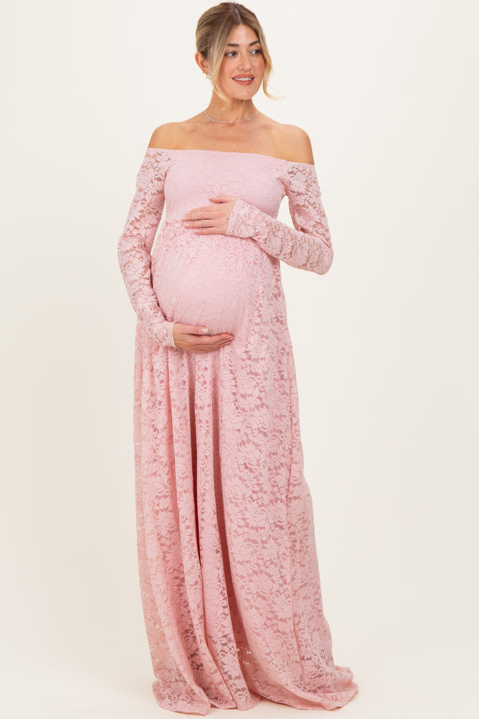 woman wearing a light pink off-the-shoulder lace maternity gown and holding her baby bump