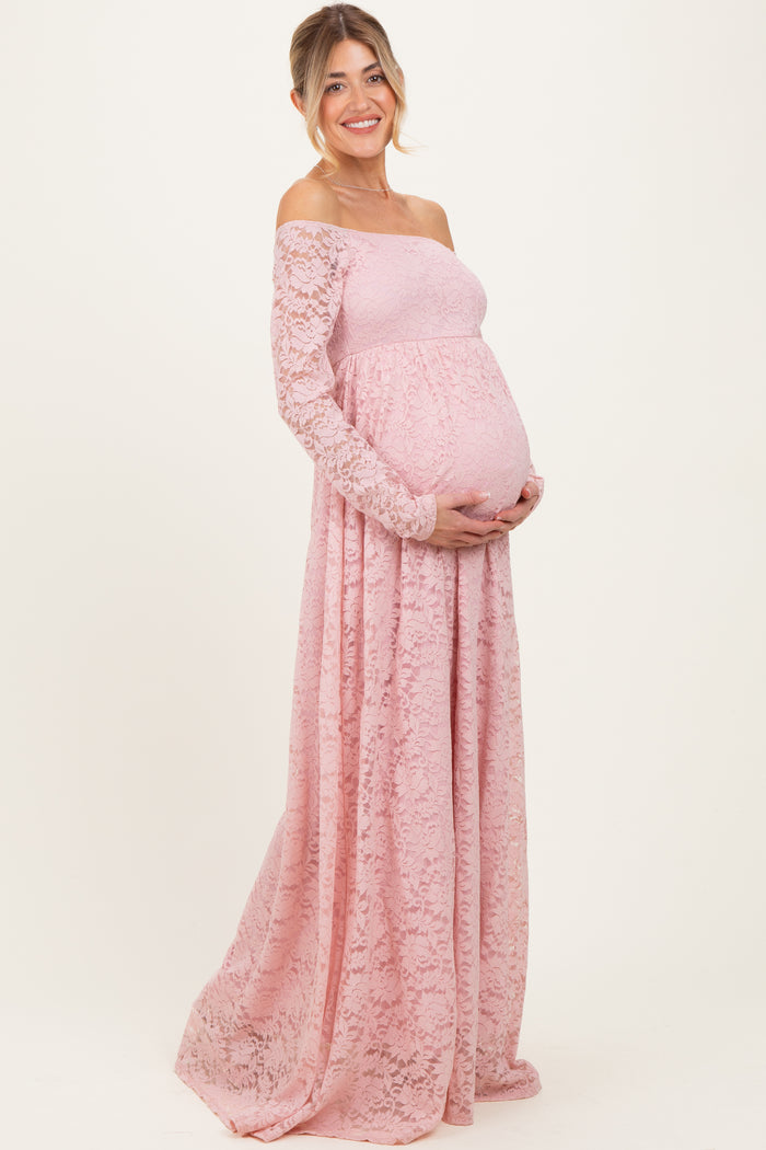 woman wearing a pink lace off-the-shoulder maternity gown and holding her baby bump