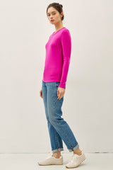 woman wearing a bright pink long sleeve top and blue jeans, paired with white sneakers