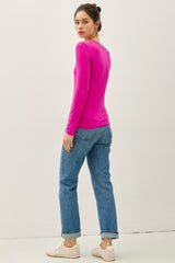 woman wearing a bright pink long sleeve top and light blue jeans, facing away from the camera