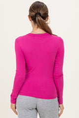 woman wearing a fitted pink long sleeve maternity top, back view, paired with gray leggings
