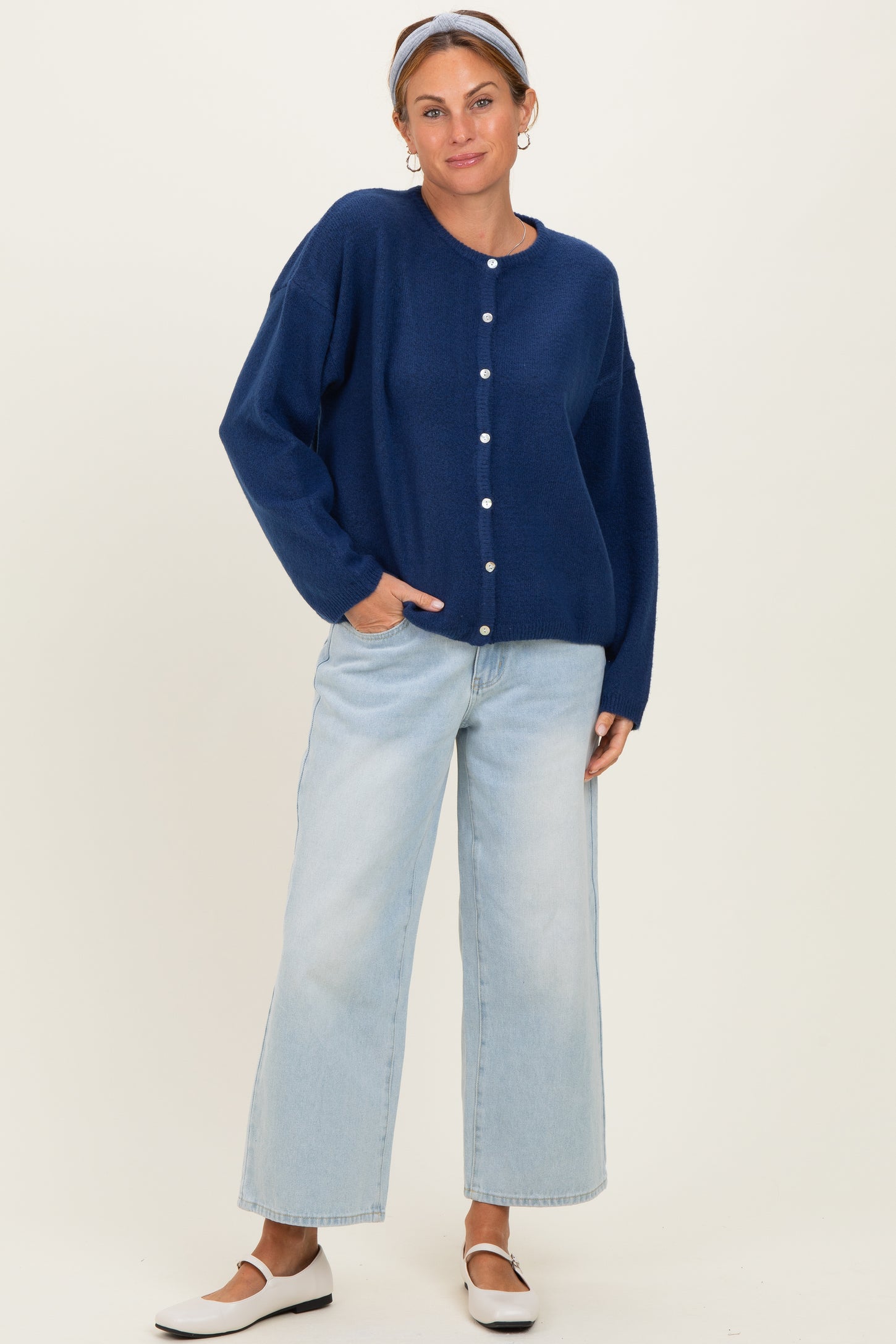 woman wearing a navy blue oversized cardigan with buttons and light blue wide-leg jeans