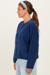 woman wearing a navy blue cardigan with button closure and loose fit, styled with a headband and light denim jeans