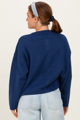 woman wearing a navy blue oversized sweater with a relaxed fit and back seam detail, styled with light blue jeans.
