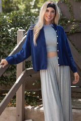 woman wearing a navy blue cardigan over a gray crop top, paired with gray wide-leg pants, smiling outdoors