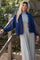 woman wearing a navy blue cardigan over a gray crop top, paired with gray wide-leg pants, smiling outdoors