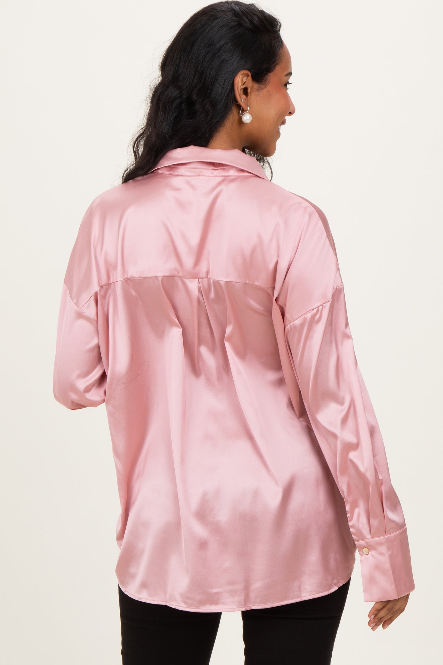 woman wearing a light pink satin maternity blouse with a relaxed fit and long sleeves, showing the back view