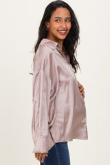 woman wearing a blush satin maternity button-up shirt and showing her baby bump