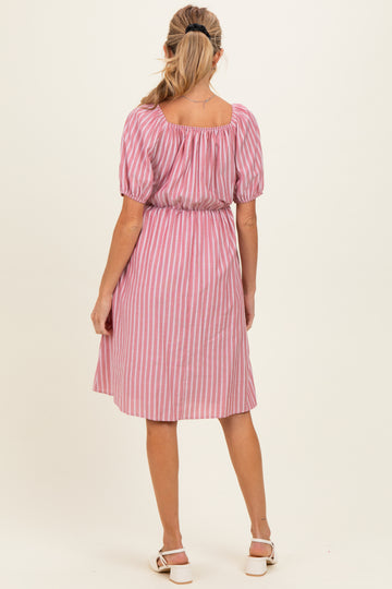 woman wearing a pink and white striped maternity dress with puff sleeves and a gathered waist, seen from the back