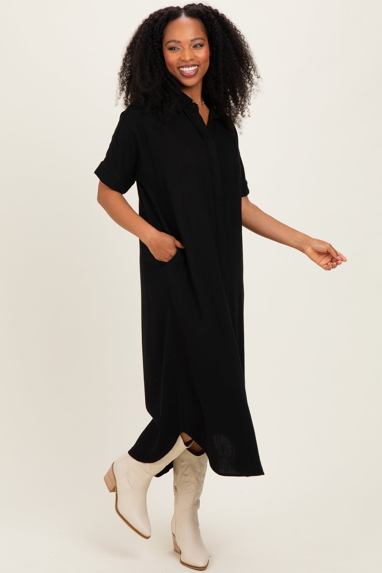 woman wearing a black short sleeve button-up maxi dress with side pockets and beige ankle booties