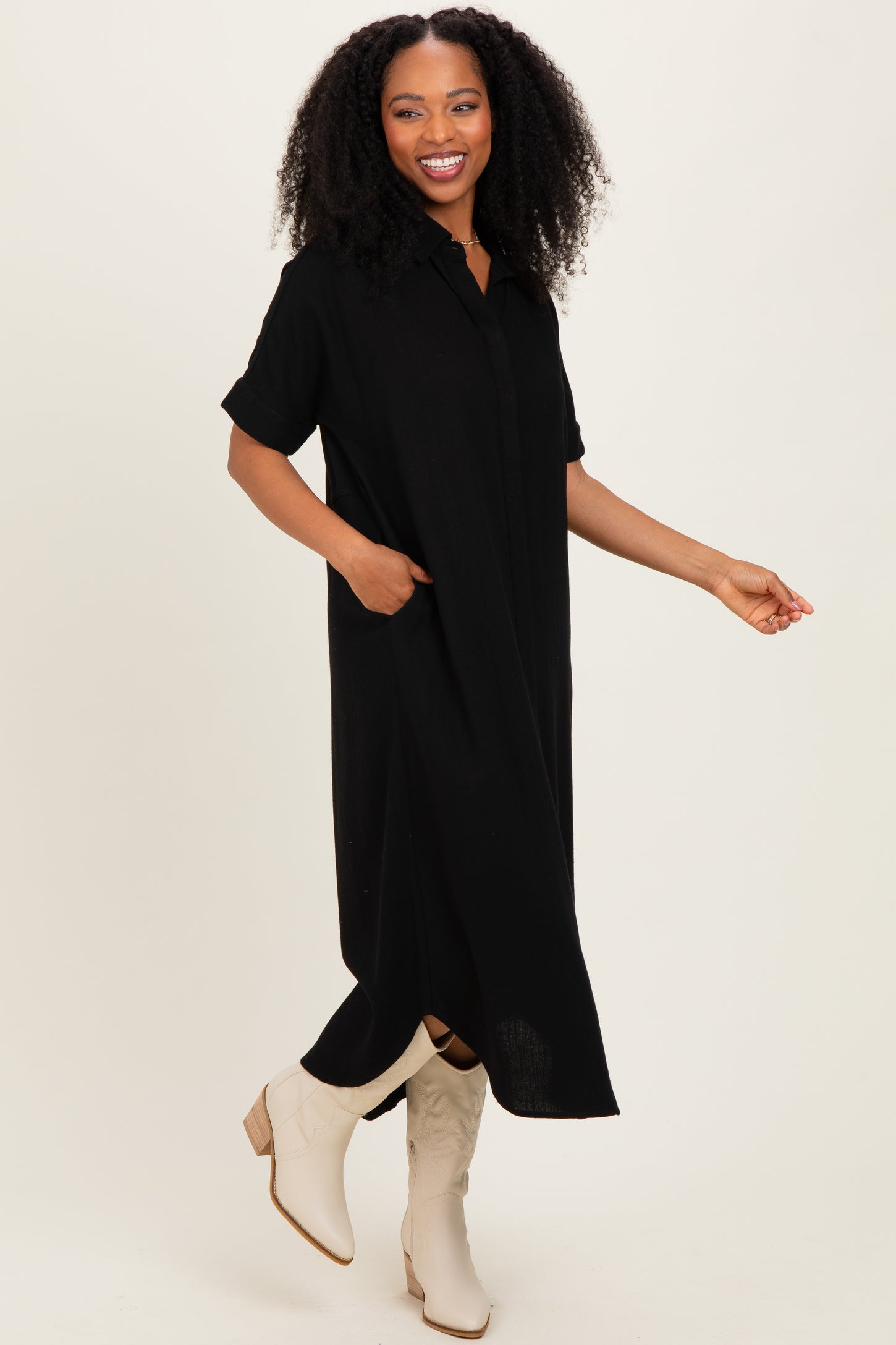 woman wearing a black short sleeve button-up maxi dress with side pockets and beige ankle booties