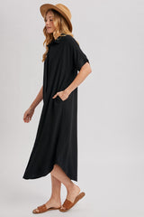 woman wearing a black midi dress with side pockets and a hood, paired with a straw hat and sandals