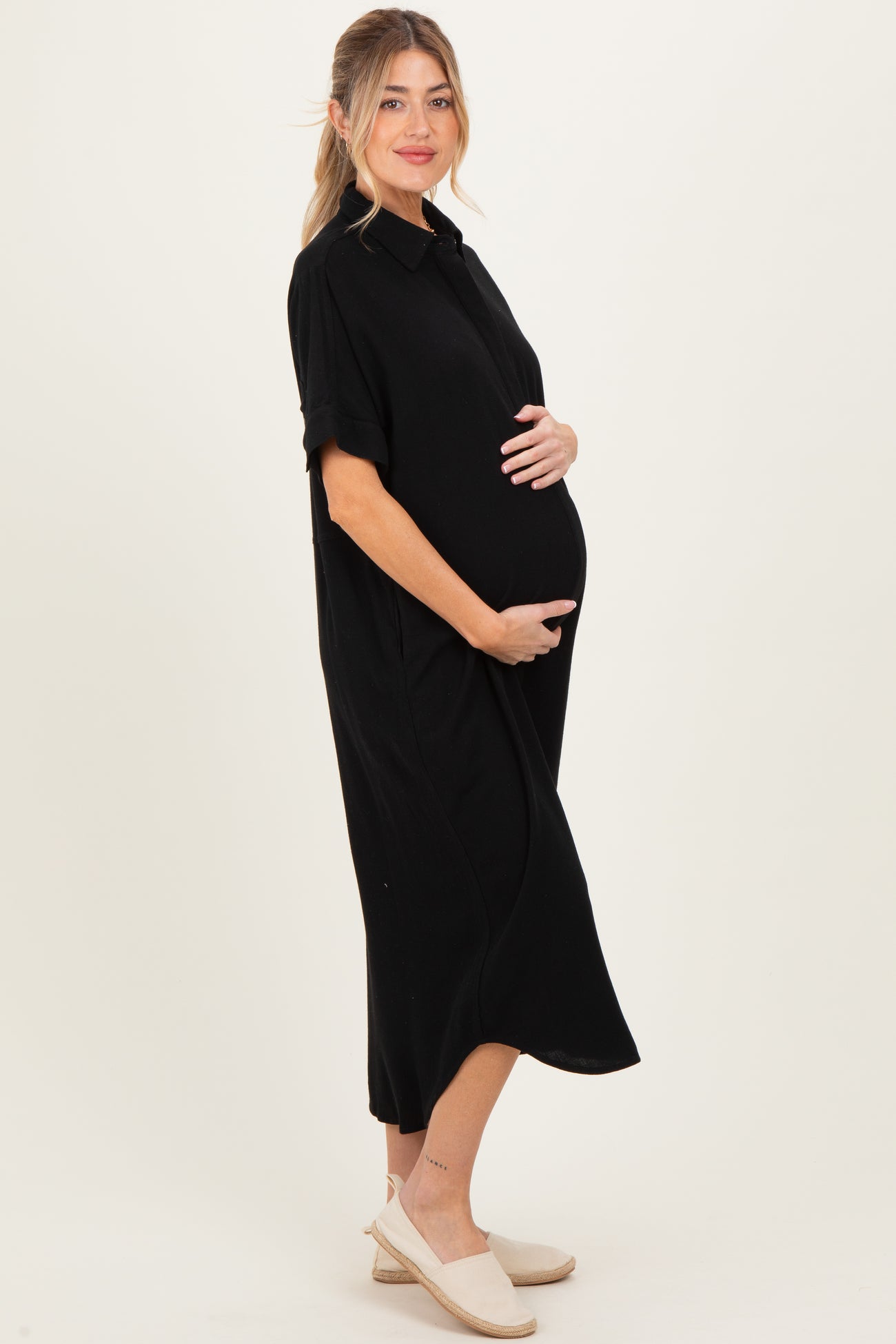 woman wearing a black short sleeve maternity dress and holding her baby bump