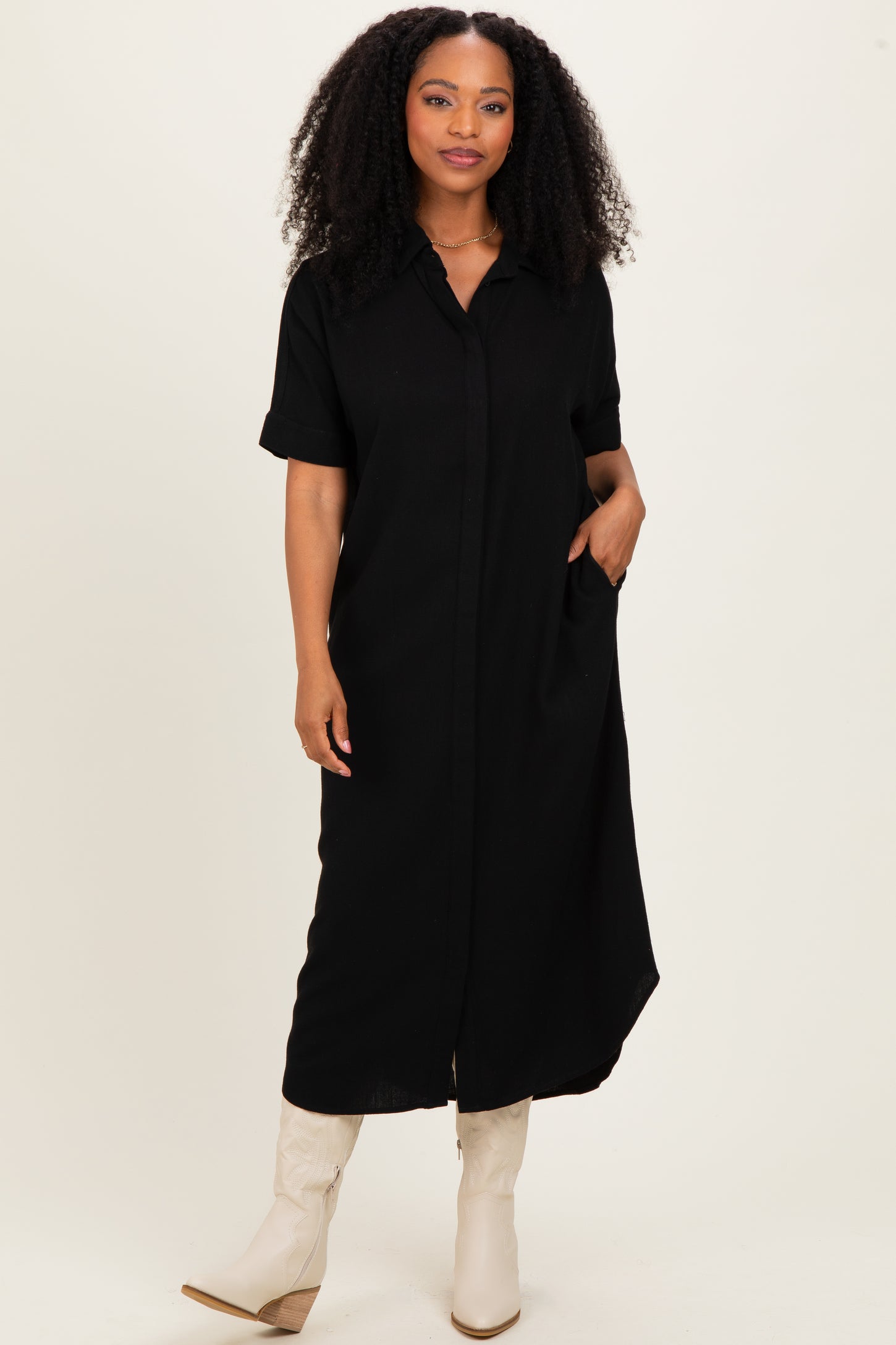 woman wearing a black short sleeve button-up maxi dress with pockets and styled with beige knee-high boots