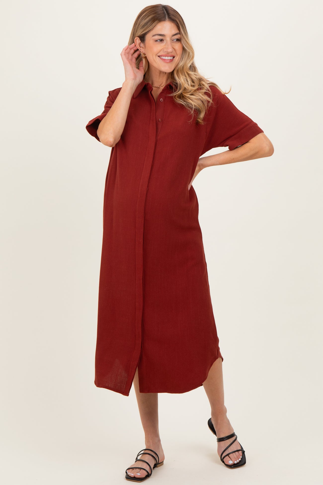 woman wearing a rust-colored short sleeve maternity dress with a button-down front and a relaxed fit, showcasing baby bump