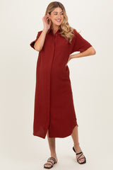 woman wearing a rust-colored short sleeve maternity dress with a button-down front and a relaxed fit, showcasing baby bump